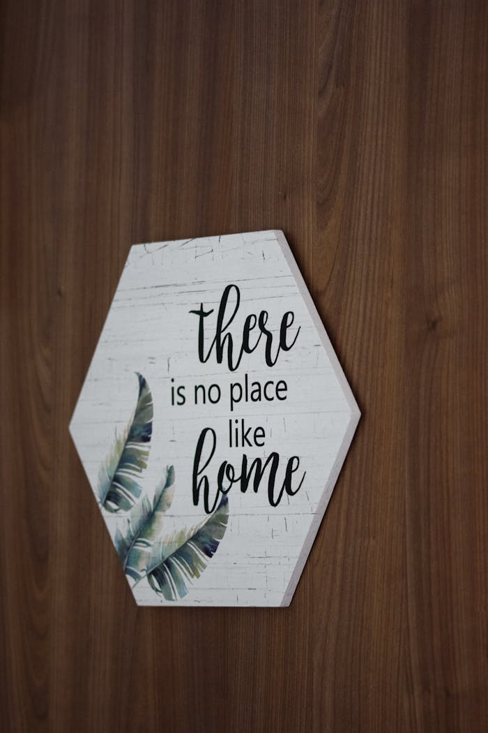 Hexagonal sign on wooden wall saying There is no place like home with leaf design.